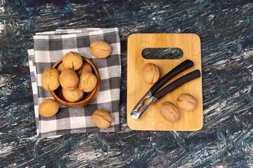 Walnut kernels on a dark table, a whole walnut in a wooden bowl. selective focus