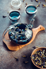 Thai Butterfly pea tea in a glass teapot and cups on a table.