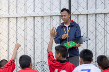 Football soccer training for kids. Coach explaining the game plan. Young boys improving soccer...