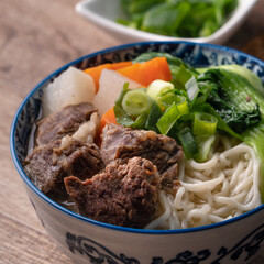 Beef noodle soup. Close up of Taiwanese famous food in a bowl on wooden table.