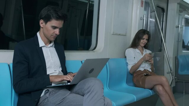 Young businessman engineer working on a laptop and listing to music in moving modern train. Shot of a businessman using a laptop while going on a business trip