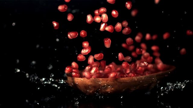 Super slow motion wooden plate with pomegranate grains drops. On a black background. Filmed on a high-speed camera at 1000 fps. High quality FullHD footage