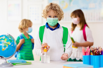 Hand sanitizer in school. Child in face mask.