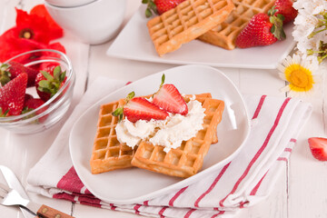 Waffles with strawberries and whipped cream.