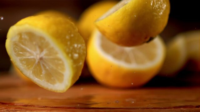Super slow motion fresh lemon falls on the table and breaks into two halves. On a wooden background. Filmed on a high-speed camera at 1000 fps. High quality FullHD footage