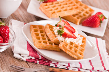 Waffles with strawberries and whipped cream.