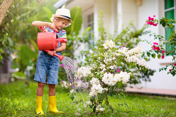 Child gardening. Boy with watering can in garden.