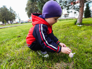 boy playing on the grass with an egg decorated in the form of a rabbit