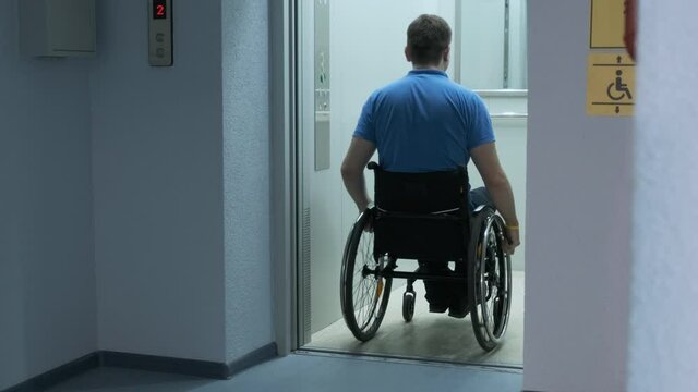 A man in a wheelchair enters the elevator. A person with a disability rides an elevator.