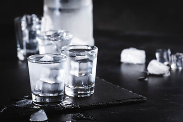 Cold Vodka in shot glasses on black background, ready to drink