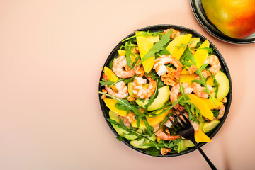 Summer Salad with Mango, Shrimps and Avocado, Walnut, Spinach and Arugula. Healthy Eating food concept Top view, pink background