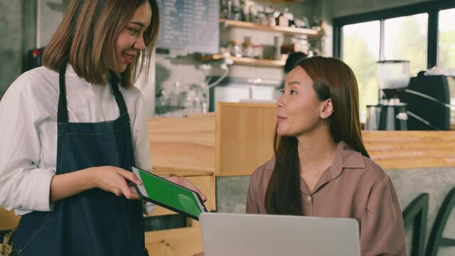 Asian female barista serving order menu  and a coffee to customer. concept of start up new business. Owner small business, food and drink, service mind concept.