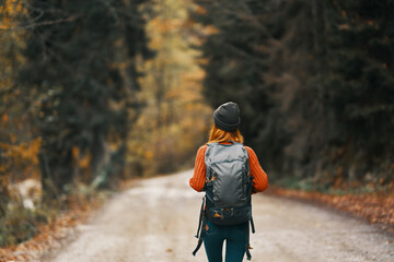 Fototapeta Traveler with a backpack in the forest on the road in autumn trees model obraz