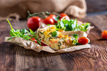 Fresh vegetable casserole with salad served on a rustic wooden board