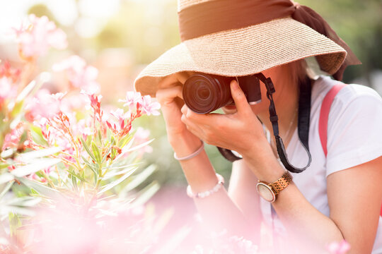 Asian girl teen tourist taking a nature photo travel while walking with hat and backpack bag