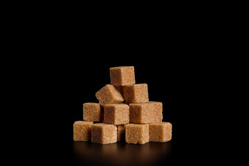 Heap of cane sugar cubes on a black background.