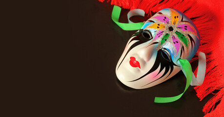 carnival colorful mask with ribbons on black background, red fringed curtain, theater poster, ticket, banner or invitation with copy space on the left