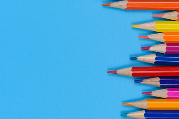 Eleven colored pencils lie in a row on a blue background.