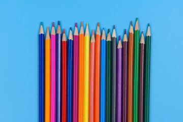 Colored pencils laid out in a row on a blue background.