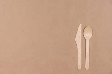 Disposable wooden spoon and knife lie on craft paper