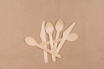 Several disposable spoons and knives lie on craft paper