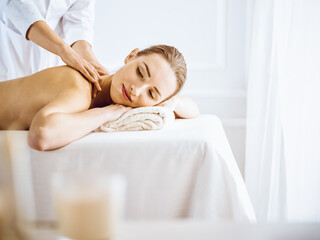 Obraz na płótnie Canvas Beautiful woman enjoying back massage with closed eyes. Spa treatment concept.