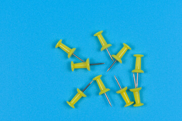 Several yellow stationery pins on blue background