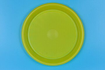 Disposable yellow plastic plate on blue background