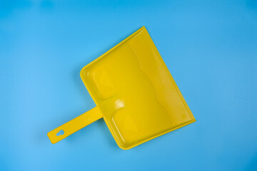 Yellow garbage scoop on blue background. View from above