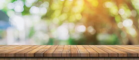 Empty wood table and defocused bokeh and blur background of garden trees with sunlight. product...