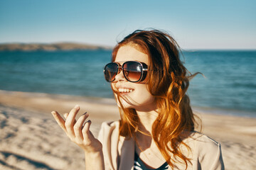 fashionable woman in glasses and in a beige coat on the seashore in the mountains close-up portrait