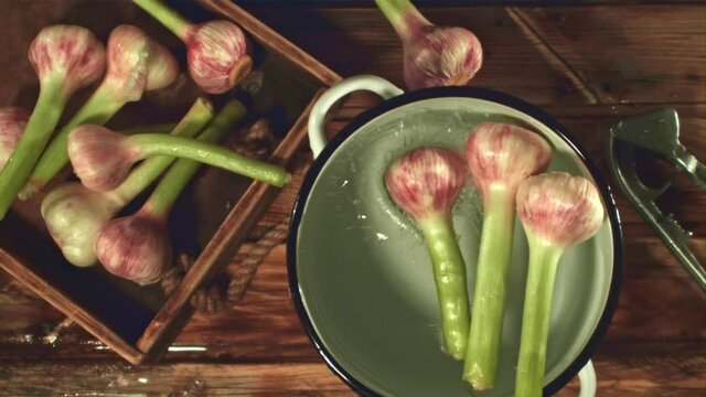 Super slow motion garlic fall into a pan with water on a wooden background. Filmed on a high-speed camera at 1000 fps. High quality FullHD footage