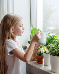 Little girl watering houseplants