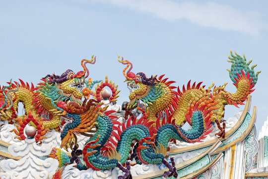 Colorful Chinese dragon statues on the roof of an ancient Buddhist temple, set against a blue sky background.