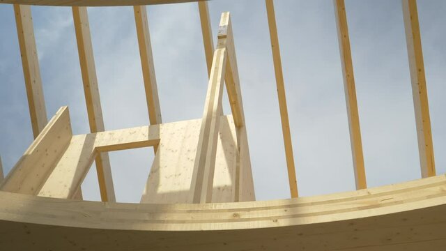 BOTTOM UP: Aluminium ladders lead up to the unfinished floor of a CLT house without a roof. Clear skies span over the hardwood roof beams of a glued-laminated timber housing project under construction