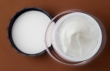 Jar of cosmetic cream on a brown background.