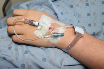 IV in a hand resting on a hospital gown.