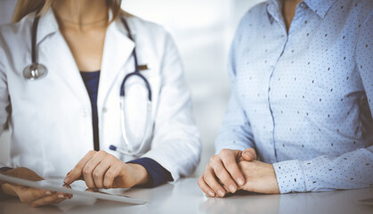 Unknown woman-doctor is showing to her patient a description of medication, while sitting together...