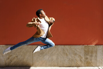 Young black man doing an acrobatic jump in the middle of the street.
