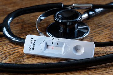 Corona Schnelltest und Stethoskop auf dem Holztisch eines Arztes COVID-19 (2019-nCoV - coronavirus...