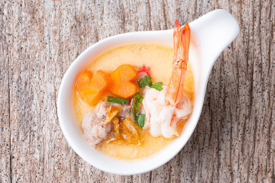 Homemade style steamed egg with shrimp and vegetables in a ceramic bowl on wooden table. healthy food concept.