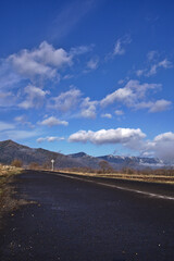 雨上がりに雲の浮かぶ青空と濡れたアスファルトの道。