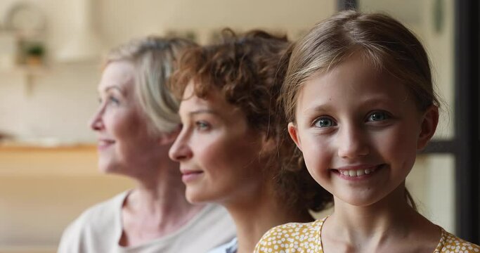 Profile faces in row three generation of women turn heads smiling looking at camera, close up. 60s grandmother, grown up daughter and little granddaughter. Multi-generational family portraits concept