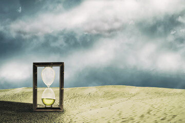 Hourglass in the sand dunes. Cloudy sky. Time concept. Business. Lifestyle.