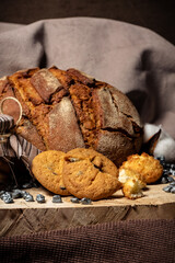 Pieces of broken biscuits lie on a wooden stump next to bread