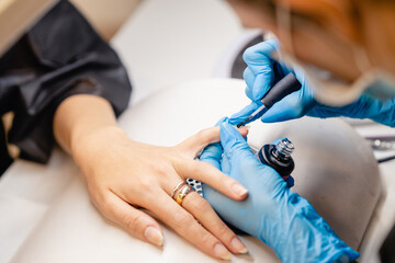 Fototapeta na wymiar Manicurist paints nails with gel polish on clients nails.