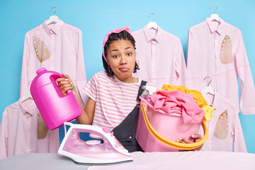 Hesitant clueless housewife with dreadlocks shrugs shoulders doesnt know what to do first stands...