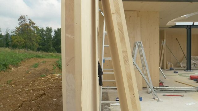 CLOSE UP: Modern cross-laminated timber house is being built in the countryside. Panning shot of rural landscape and the construction site of a contemporary prefabricated lumber real estate project.