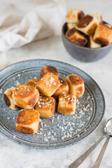 Square curd pancakes, traditional Russian cheese cakes in a gray plate and bowl, with coconut flakes. On a light background with instruments, vertical arrangement