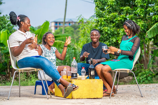 selective focus of african youth, with drinks and cups on yellow box- candid image of black ladies and a guy outdoor having fun- partying concept 